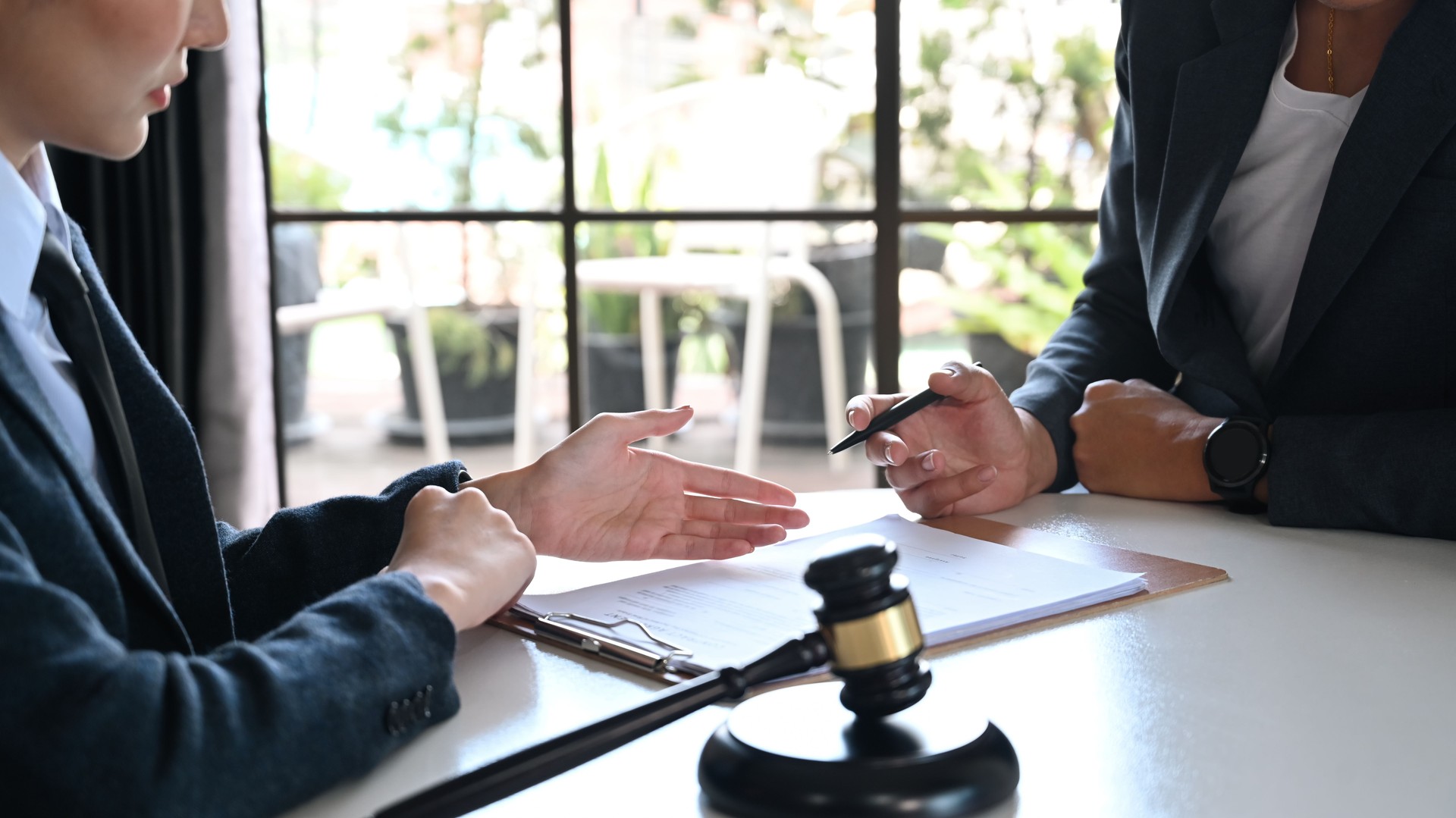 Female lawyer explaining terms, condition on legal document to client before signing on contract at law firm.